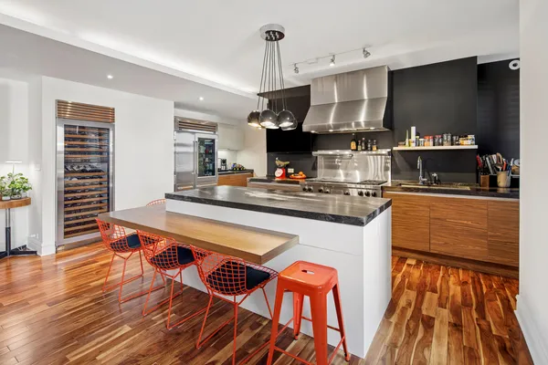 a kitchen with stainless steel appliances a kitchen island hardwood floor sink stove dining table and chairs