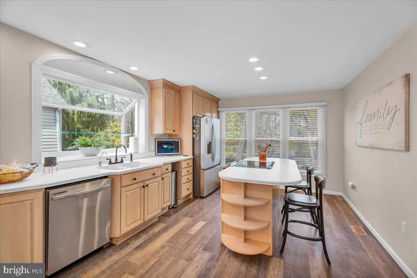 a large white kitchen with sink a window and dining table