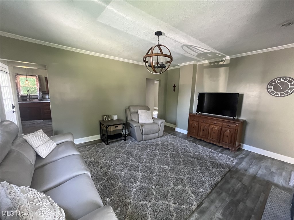 4440 Dryden Court Southwest Canton, OH 44708 - Photo 9 of 28 Living area with crown molding, a textured ceiling, wood finished floors, and a chandelier