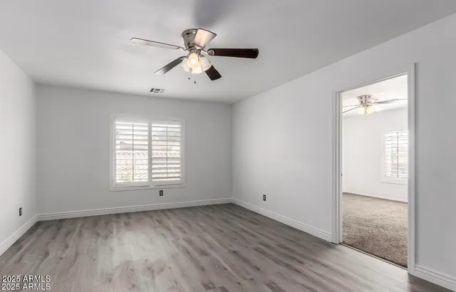 a view of an empty room with a window and wooden floor