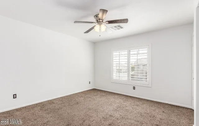 an empty room with fan and windows