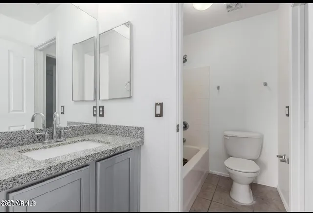 a bathroom with a granite countertop sink a toilet and a mirror
