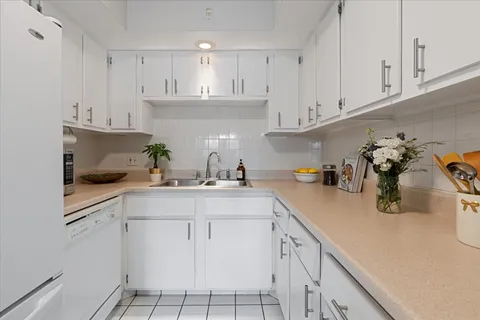 a kitchen with white cabinets and sink