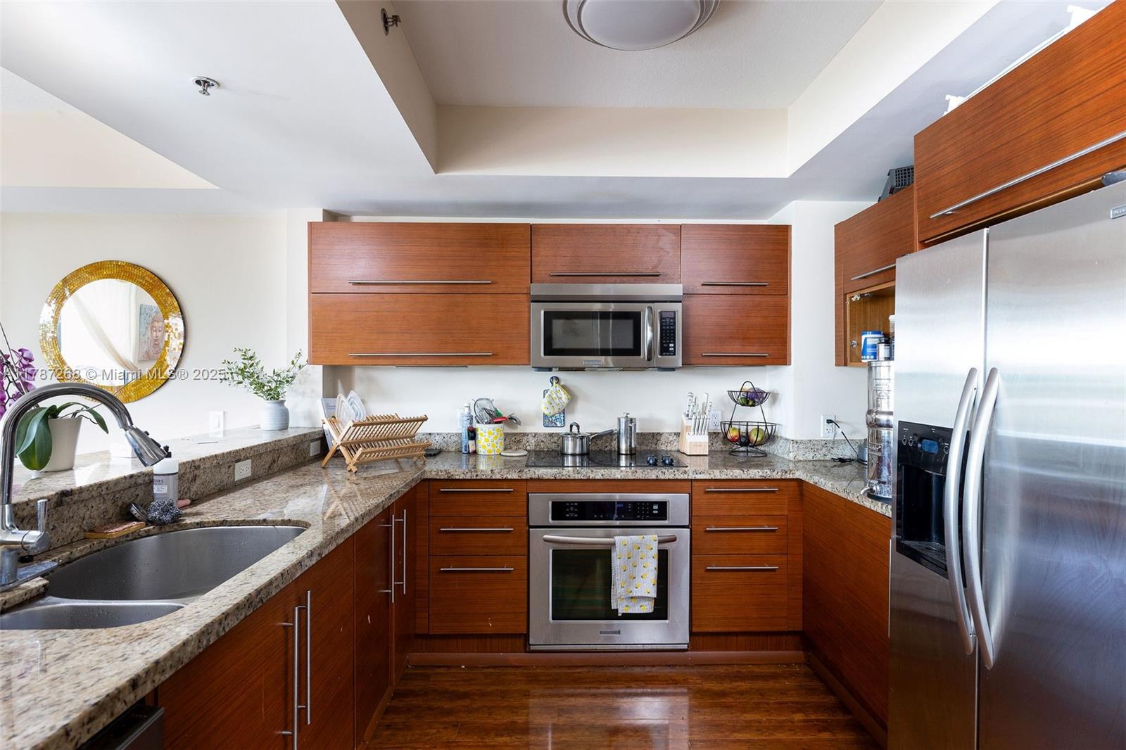 2681 North Flamingo Road, Unit TH4S Sunrise, FL 33323 - Photo 3 of 27 a kitchen with stainless steel appliances granite countertop a sink a stove top oven a refrigerator with wooden cabinets and floor