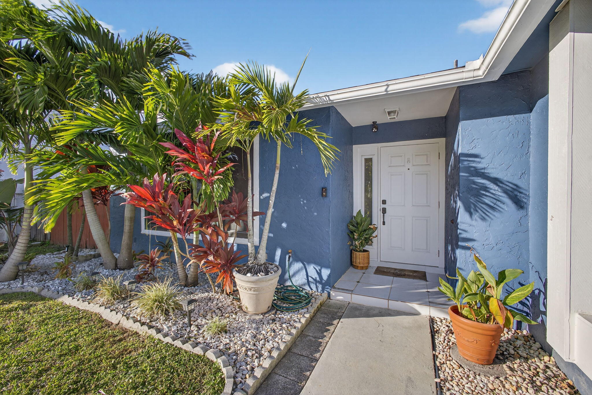 154 Rosewood Circle Jupiter, FL 33458 - Photo 1 of 43 a potted plant sitting in front of a house
