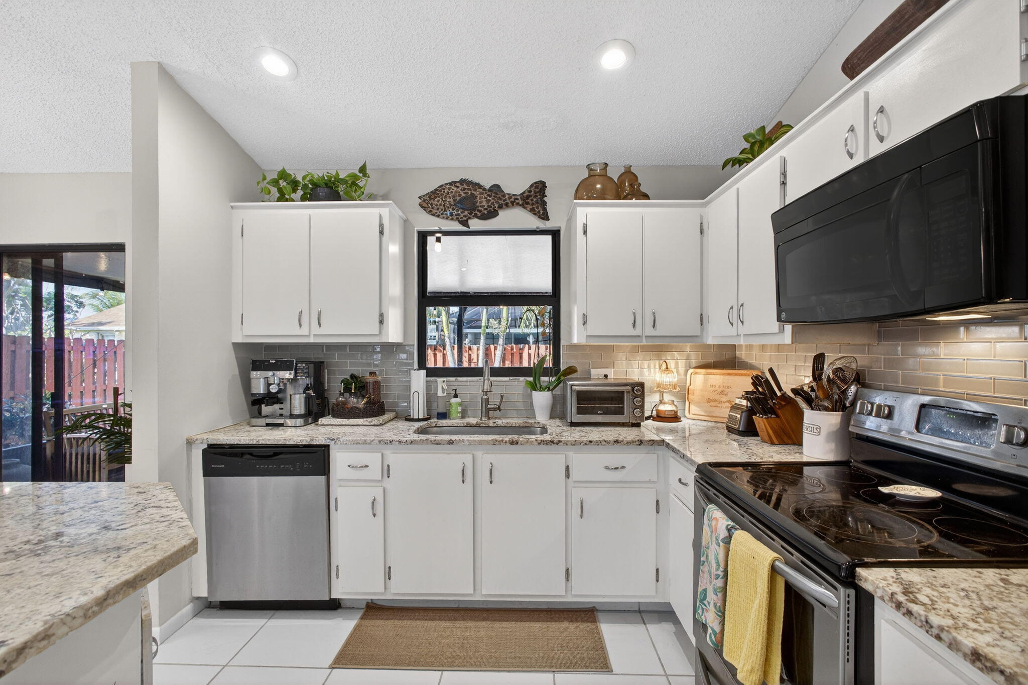 154 Rosewood Circle Jupiter, FL 33458 - Photo 16 of 43 a kitchen with stainless steel appliances granite countertop a sink stove top oven and cabinets
