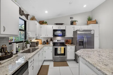 a kitchen with stainless steel appliances granite countertop a refrigerator and a stove top oven