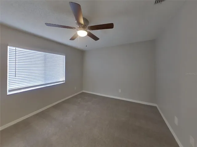an empty room with a window and a fan