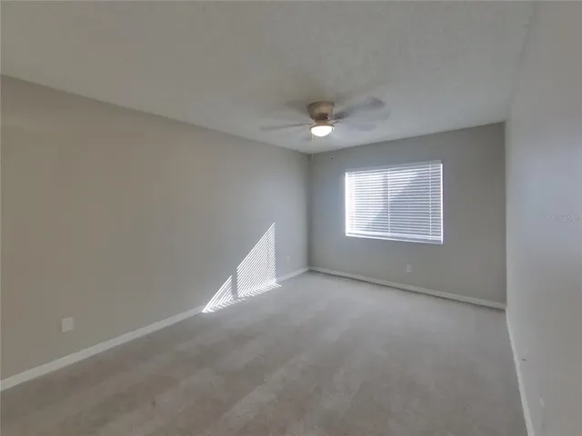 en empty room with windows and ceiling fan