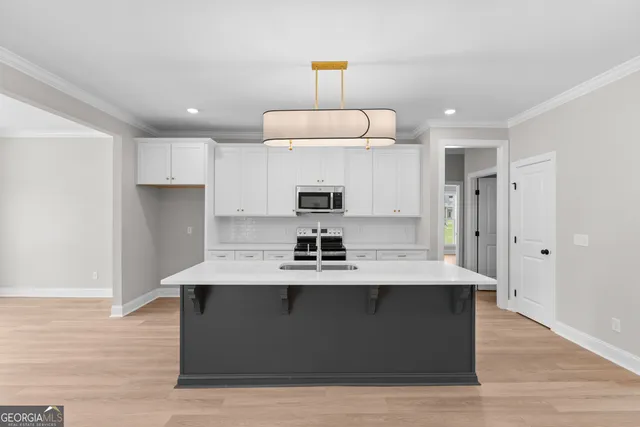 a view of a kitchen counter space a sink wooden floor and a refrigerator