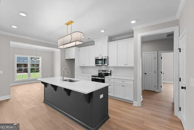 a kitchen with stainless steel appliances a sink a stove a refrigerator cabinets and wooden floor