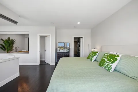 a large white room with bed and wooden floor