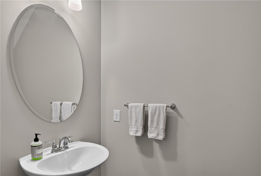 112 Tuttle Street Clemson, SC 29631 - Photo 18 of 46 A sleek pedestal sink with a contemporary oval mirror creates a clean, functional bathroom space.