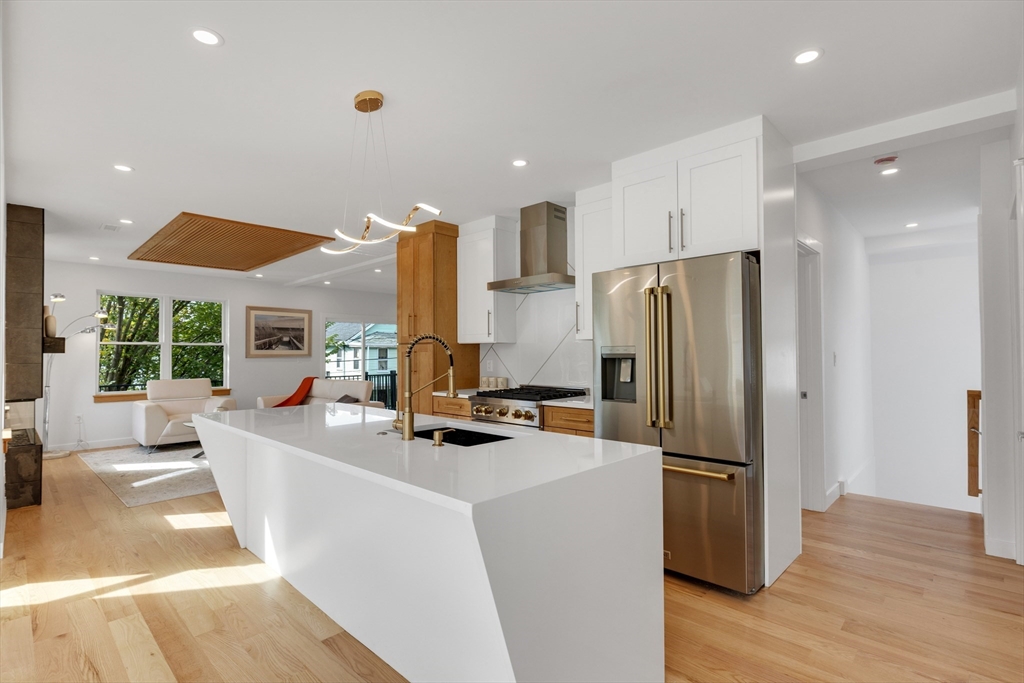69 Boston Avenue, Unit 69 Somerville, MA 02144 - Photo 6 of 26 a kitchen with stainless steel appliances a refrigerator a stove a oven and a sink with wooden floor