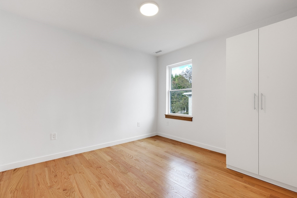 69 Boston Avenue, Unit 69 Somerville, MA 02144 - Photo 7 of 26 an empty room with wooden floor and windows