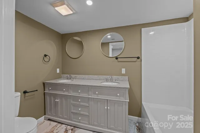 a bathroom with a granite countertop sink a toilet and a mirror