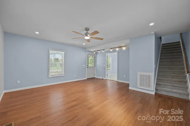 a view of an empty room with a window and wooden floor