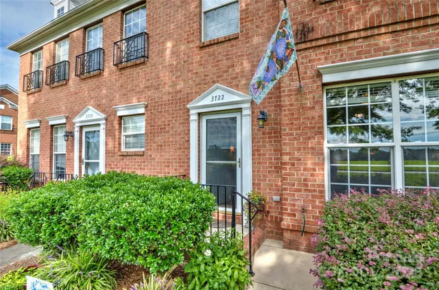 a view of a brick house with large windows and plants