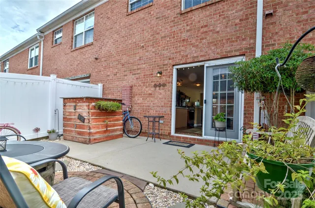 a view of a brick house with chairs and table in a patio