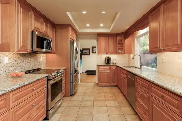 a kitchen with stainless steel appliances granite countertop a stove a sink and a microwave