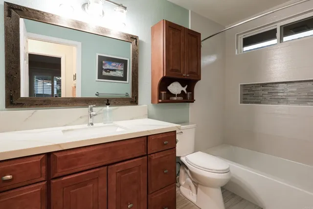 a bathroom with a granite countertop sink a toilet and a mirror