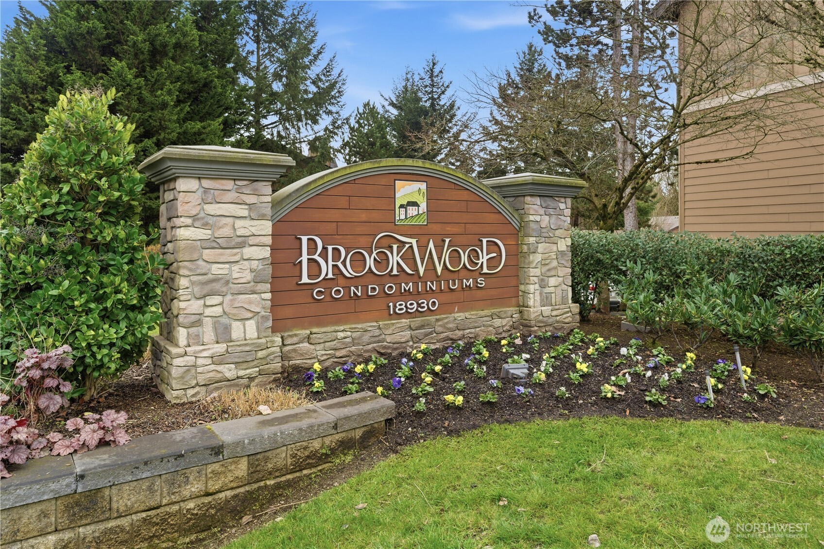 18930 Bothell Everett Highway, Unit G105 Bothell, WA 98012 - Photo 2 of 21 a blue sign that is sitting on a brick wall