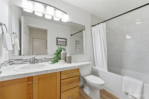 a bathroom with a sink a toilet a mirror a vanity and shower