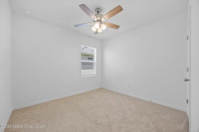 an empty room with closet and a chandelier fan