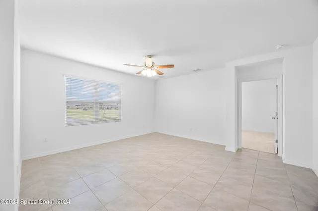 an empty room with a ceiling fan and window