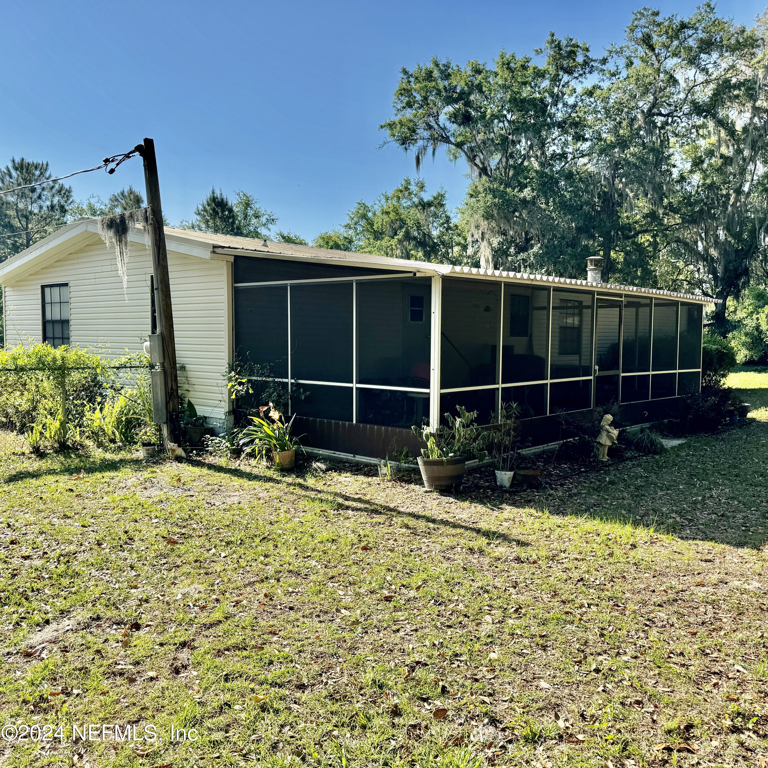 105 George Avenue Interlachen, FL 32148 - Photo 2 of 29 a view of a backyard with potted plants and a large tree