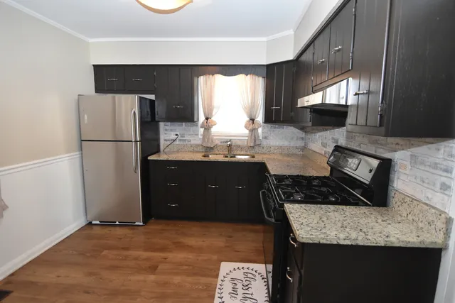 a kitchen with granite countertop a refrigerator a stove and a sink