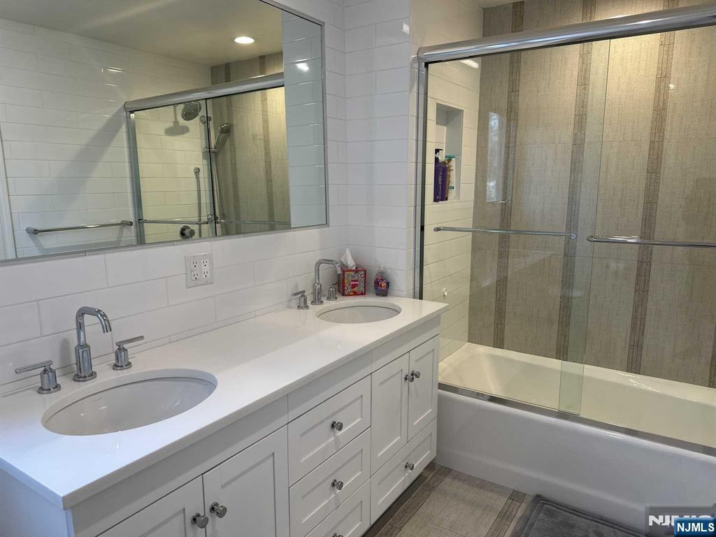 711 Camperdown Road Teaneck, NJ 07666 - Photo 11 of 12 a bathroom with a double vanity sink and mirror with bathtub