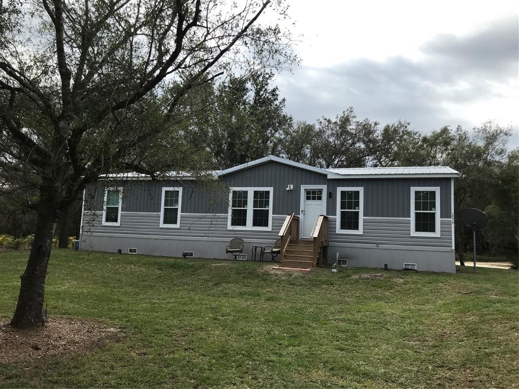 a front view of house with yard and trees all around