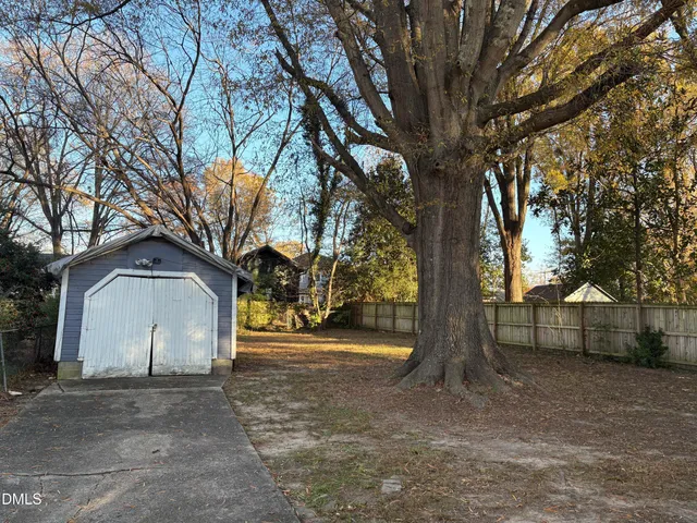 a view of a white house with a large tree