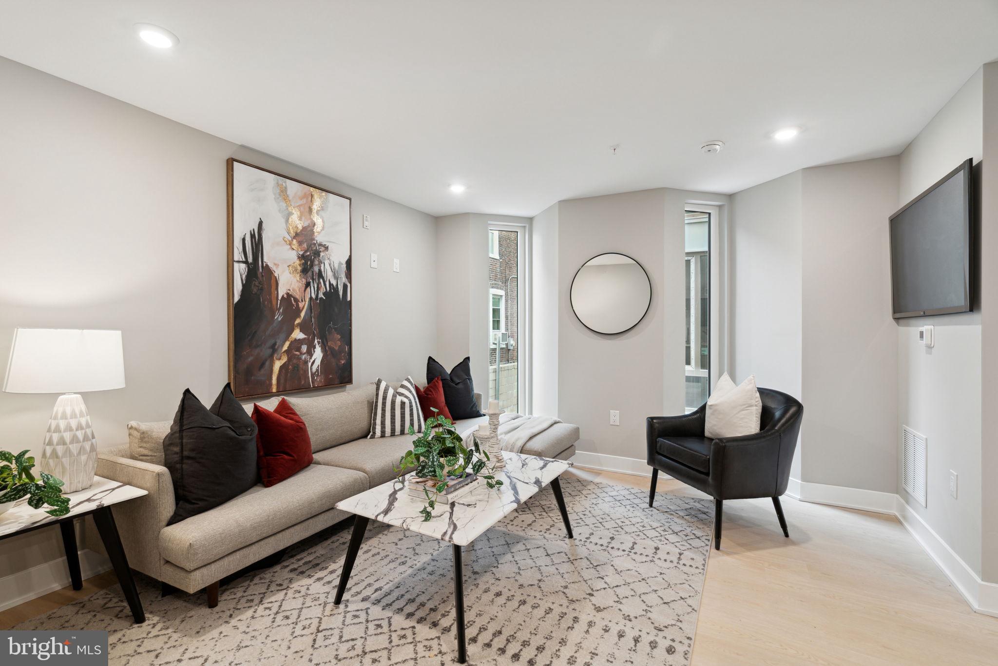 6604 Ridge Avenue, Unit 410 Philadelphia, PA 19128 - Photo 19 of 32 a living room with furniture a mirror and a flat screen tv