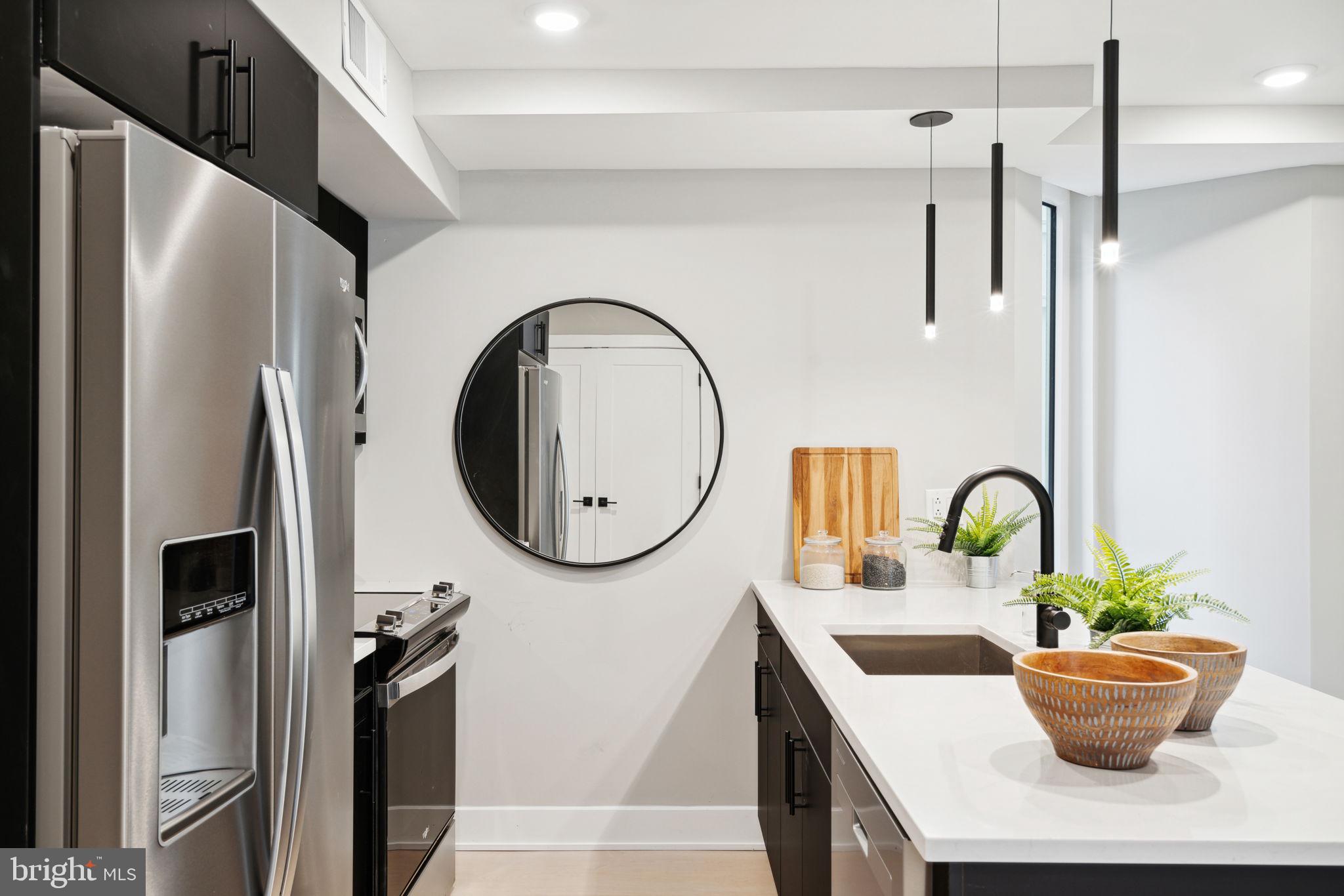 6604 Ridge Avenue, Unit 410 Philadelphia, PA 19128 - Photo 7 of 32 a dining table with a potted plant on a counter and a sink