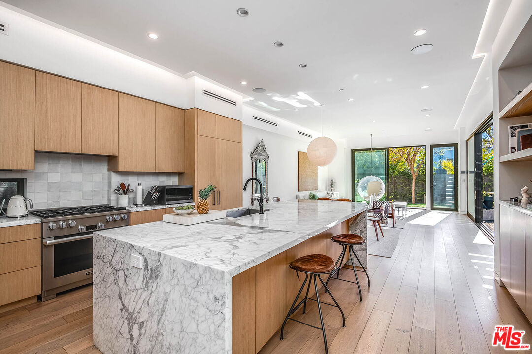 1620 Electric Avenue Venice, CA 90291 - Photo 9 of 24 a kitchen with stainless steel appliances granite countertop a stove top oven a sink dishwasher a dining table and chairs with wooden floor