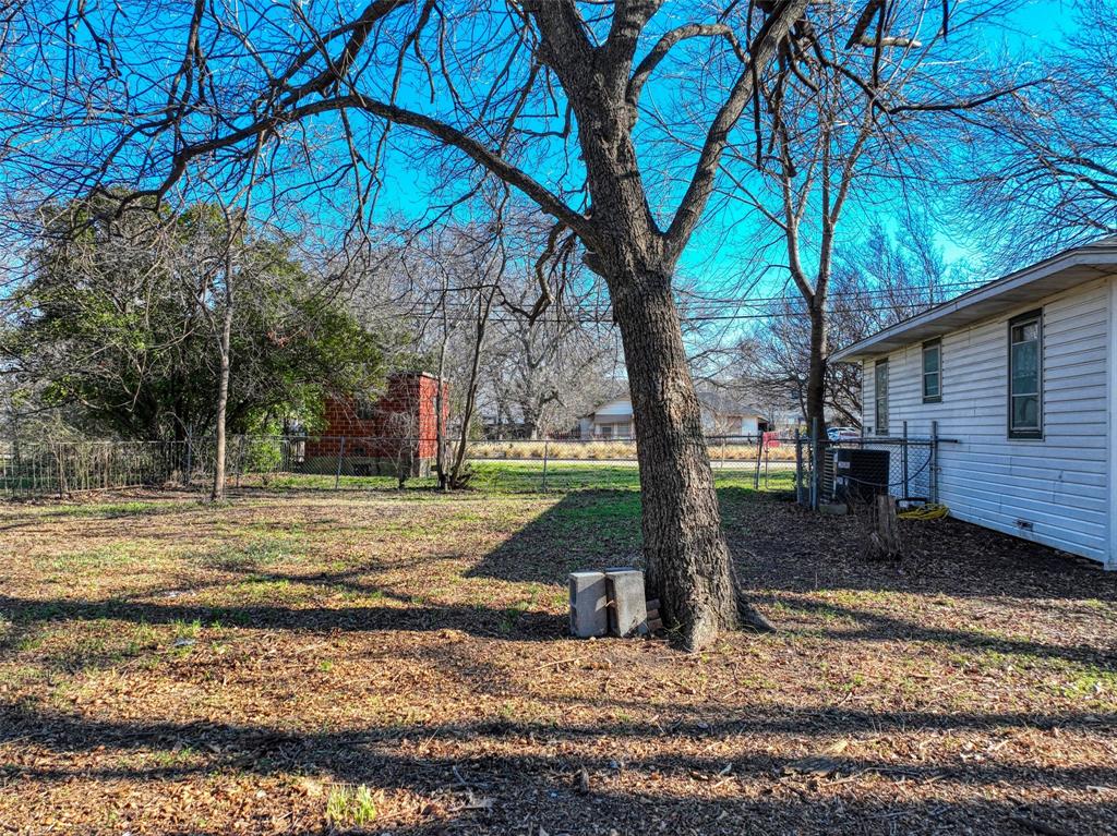 305 East Belt Line Road Wilmer, TX 75172 - Photo 9 of 16 a view of a yard with plants and a large tree