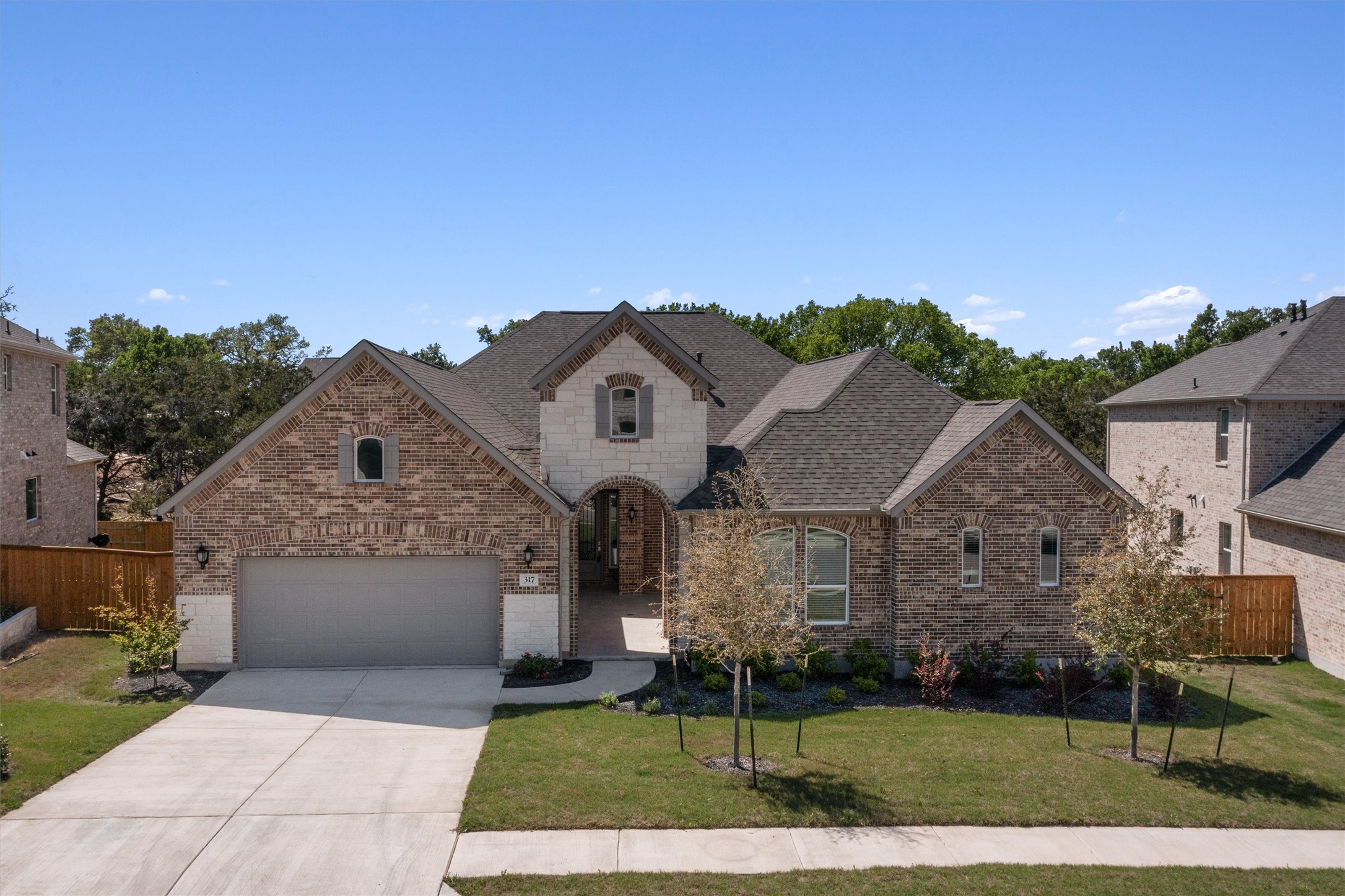 317 Pigeon River Road Kyle, TX 78640 - Photo 1 of 1 Multi-textured brick and stone elevations establish classic curb appeal under a clear blue sky.