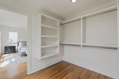 a view of an empty room with wooden floor and a closet