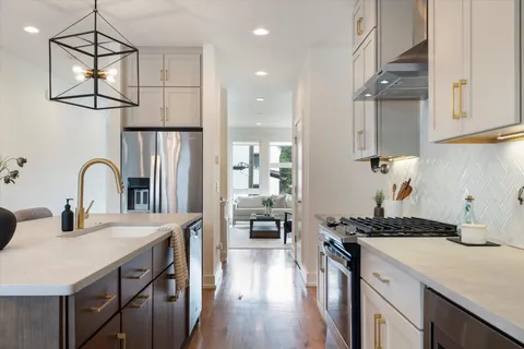 a kitchen with stainless steel appliances a sink a stove cabinets and wooden floor