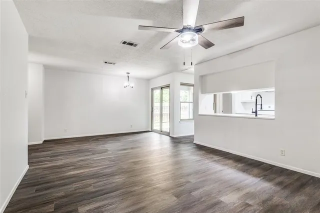 a view of an empty room with window and wooden floor