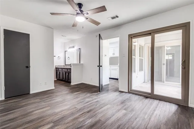a view of a big room with wooden floor a ceiling fan and windows