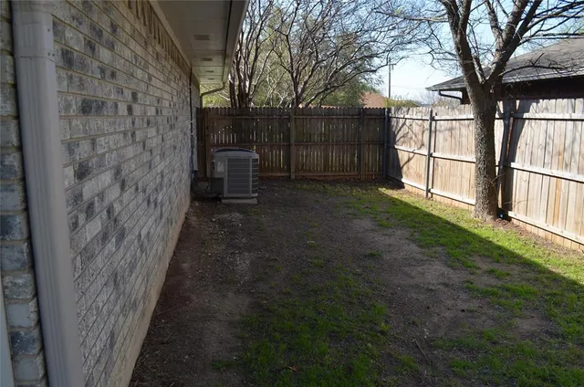 a view of a yard with wooden fence and a large tree