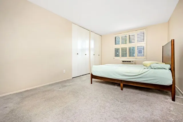 a bed sitting in a spacious bedroom next to a window and a chair