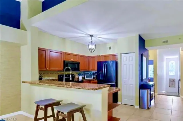 a kitchen with stainless steel appliances granite countertop a refrigerator a stove a sink a dining table and chairs with wooden floor