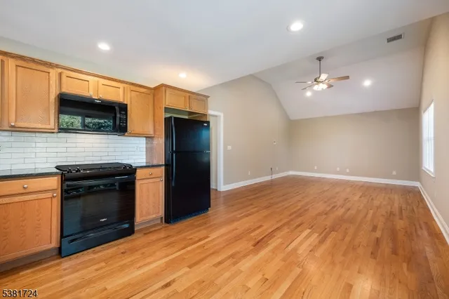 a kitchen with granite countertop a stove top oven a sink dishwasher a refrigerator and a fireplace with wooden floor