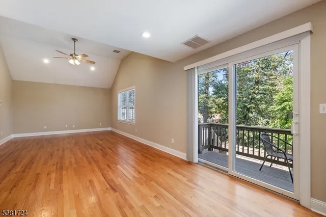 a view of empty room with wooden floor and fan