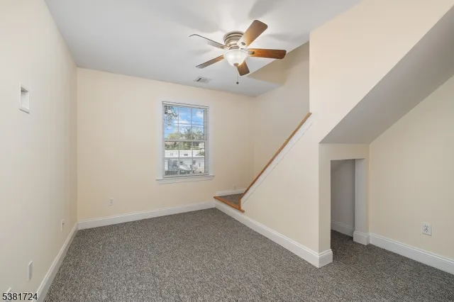 an empty room with ceiling fan and window