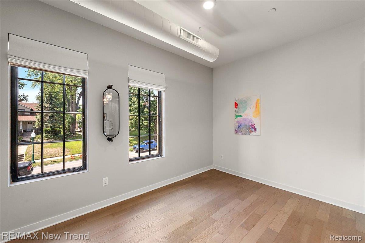 804 North Main Street, Unit 2H Rochester, MI 48307 - Photo 24 of 52 Wood-finish flooring with white baseboards, light grey walls, and two large windows with dark grid frames